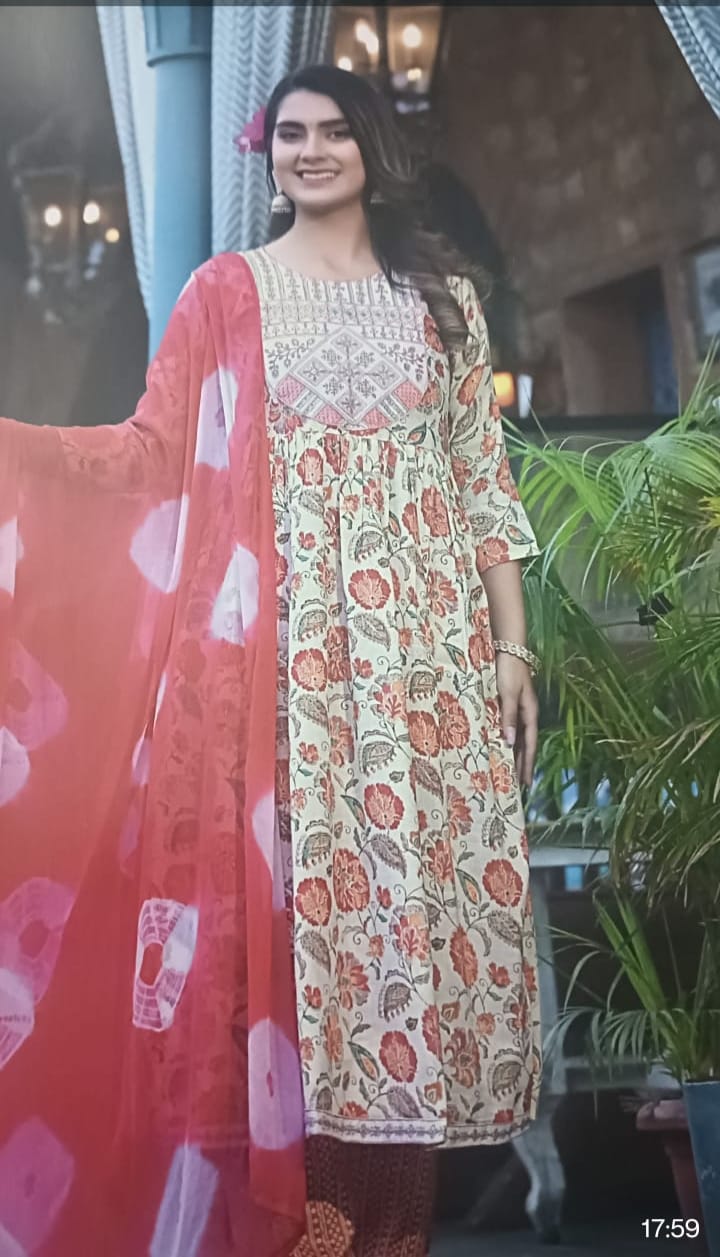 Woman in a floral dress with a red dupatta standing outdoors.