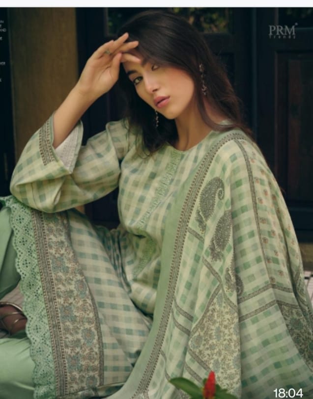 Woman wearing a green patterned outfit sitting indoors.