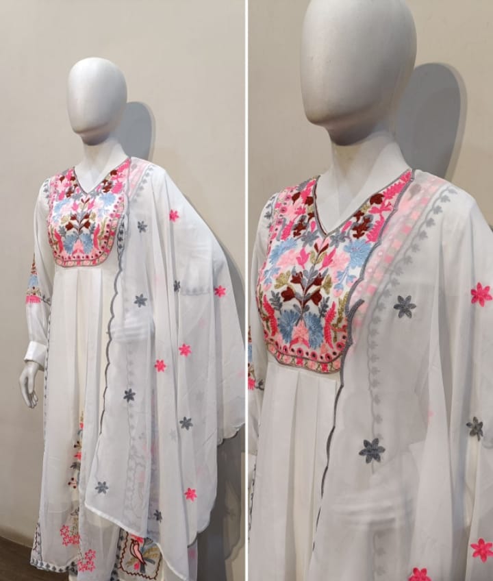 White embroidered outfit with colorful patterns on a mannequin against a neutral background